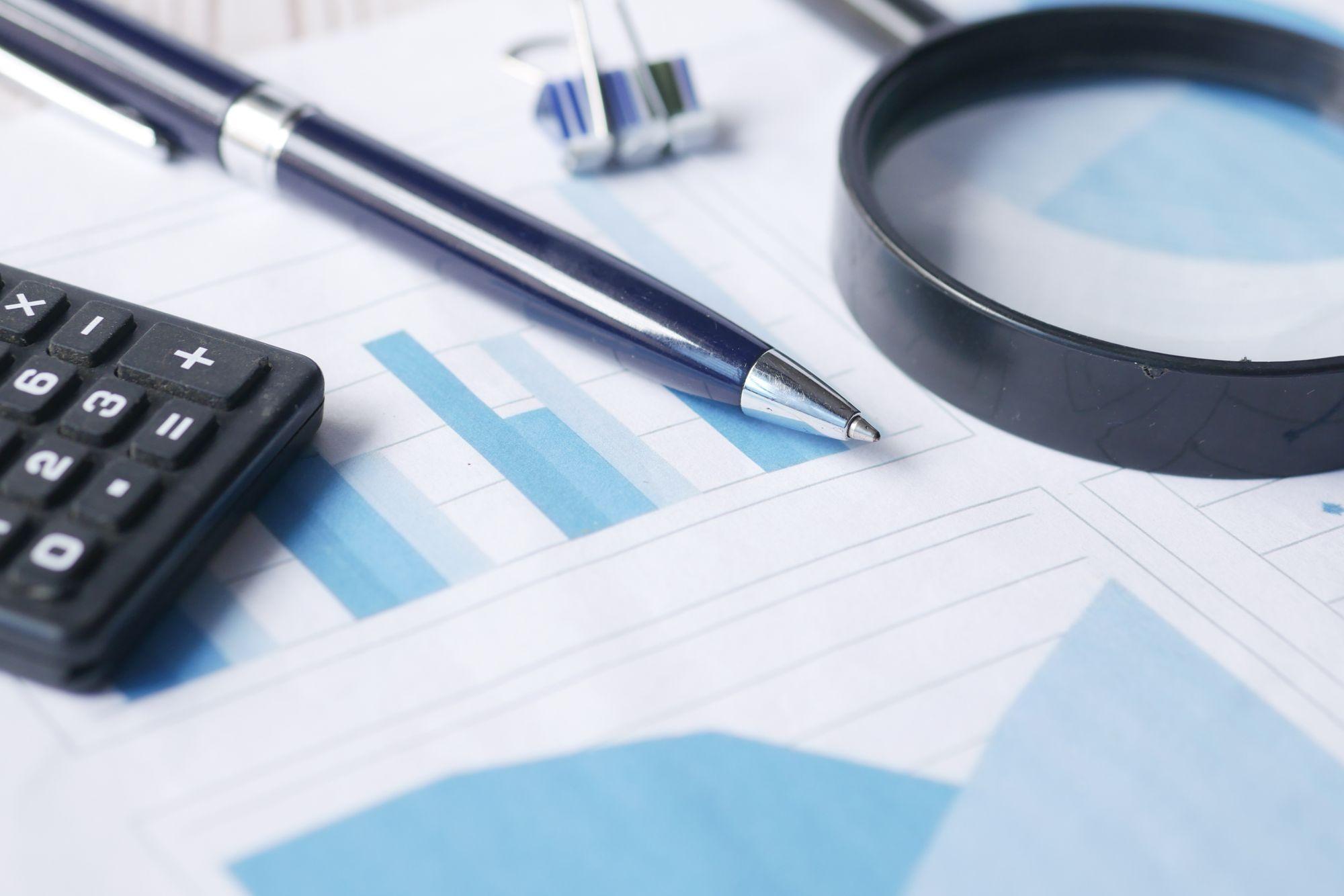 Magnifying glass over financial charts, representing Edu Accounting & Auditors' audit and assurance services
