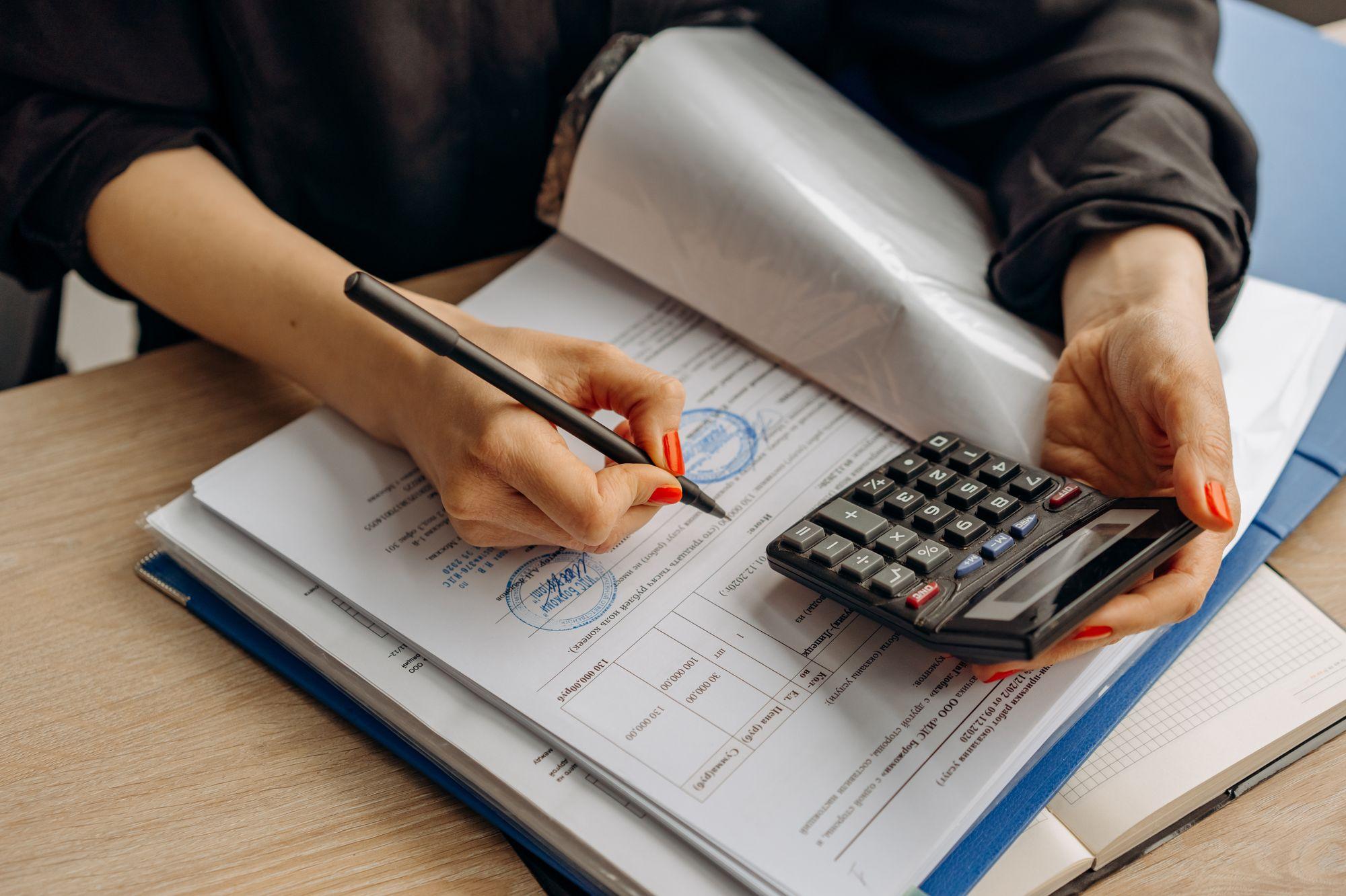 Accountant reviewing financial documents with a calculator, representing Edu Accounting & Auditors' bookkeeping services
