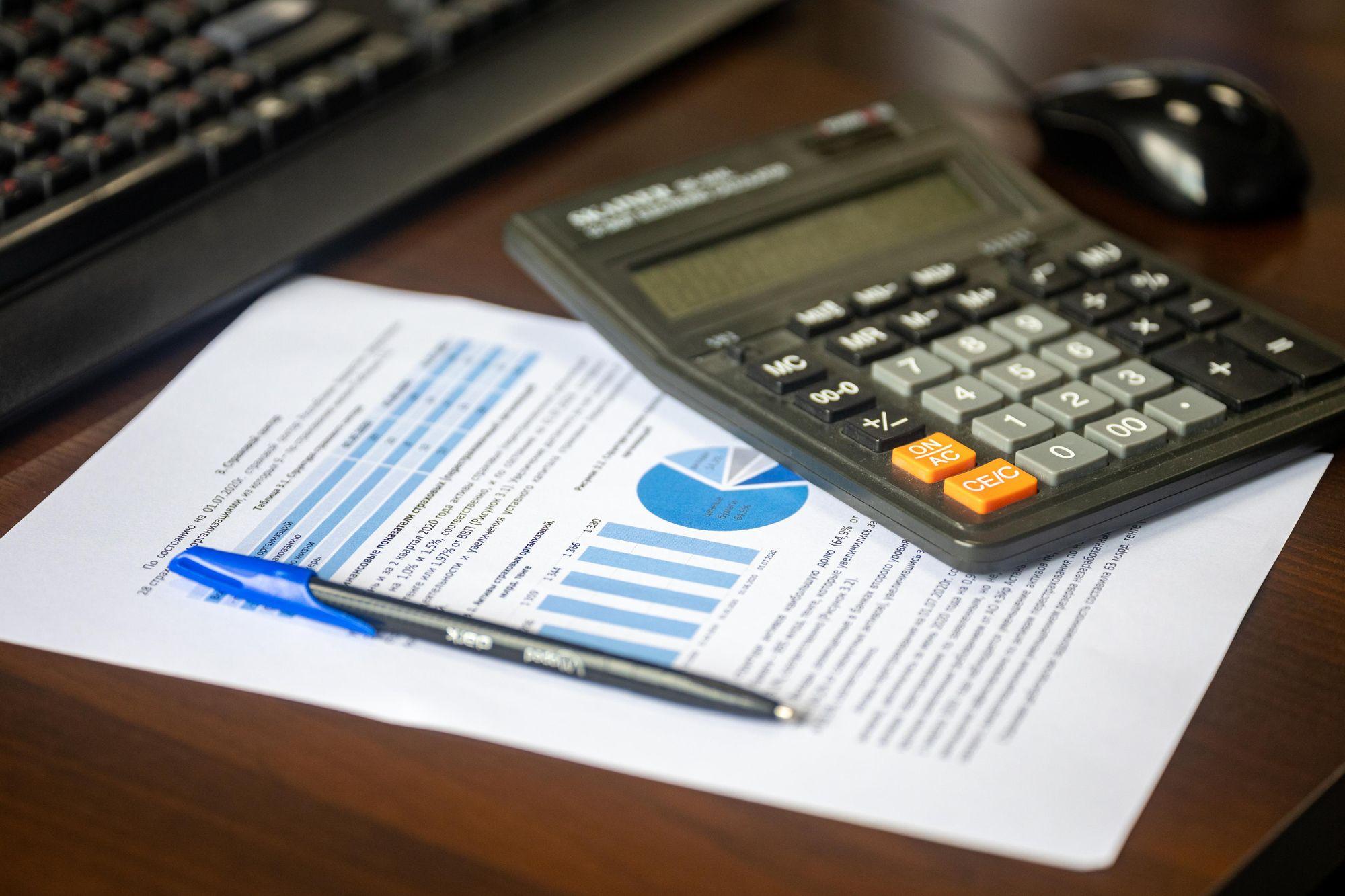 Calculator and financial report on a desk, representing Edu Accounting & Auditors' payroll services