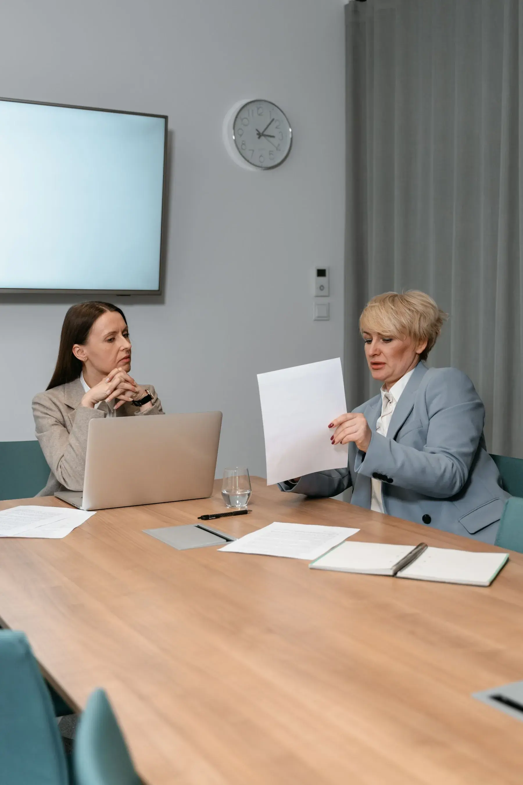 Two professionals reviewing a document together at a boardroom table, representing Edu Accounting & Auditors' audit and assurance services