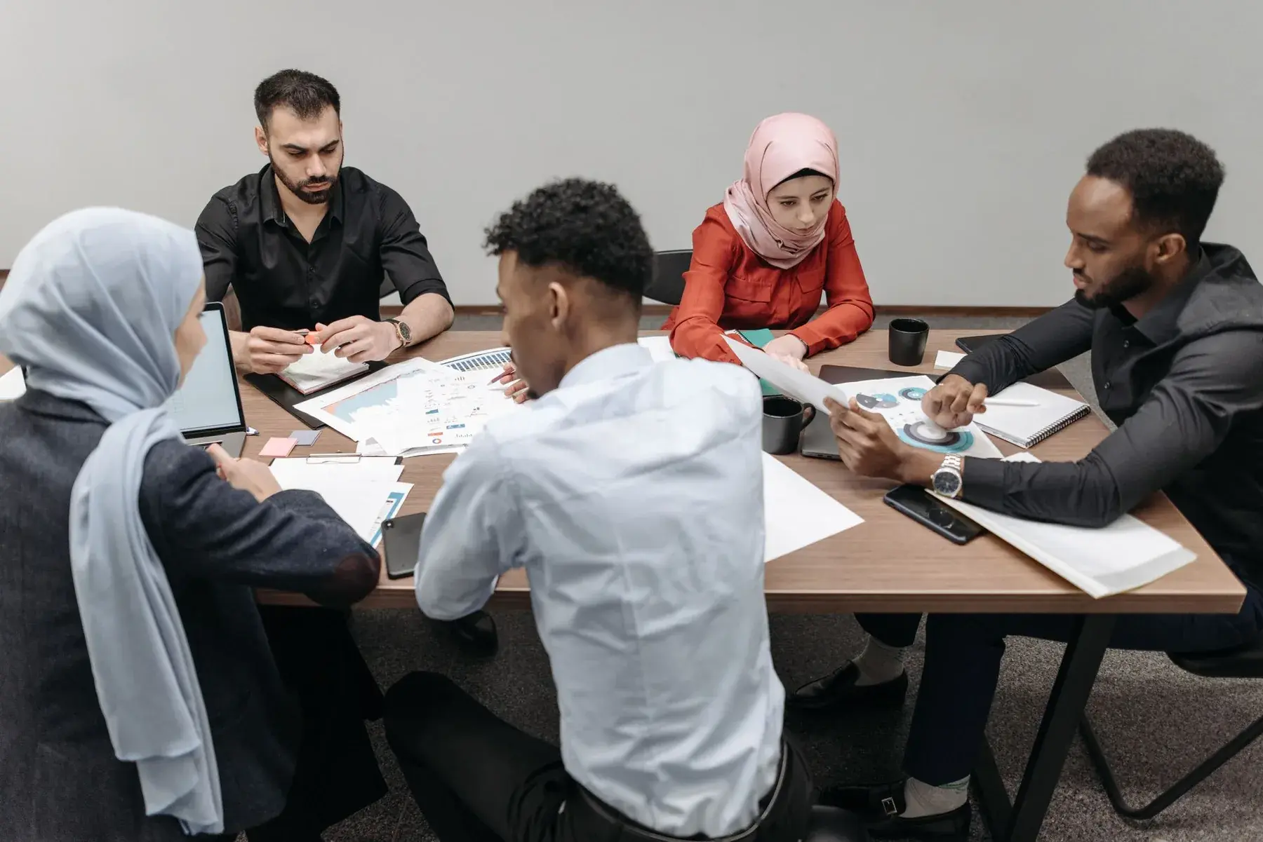 A diverse group of professionals collaborating around a table, representing Edu Accounting & Auditors' B-BBEE advisory services