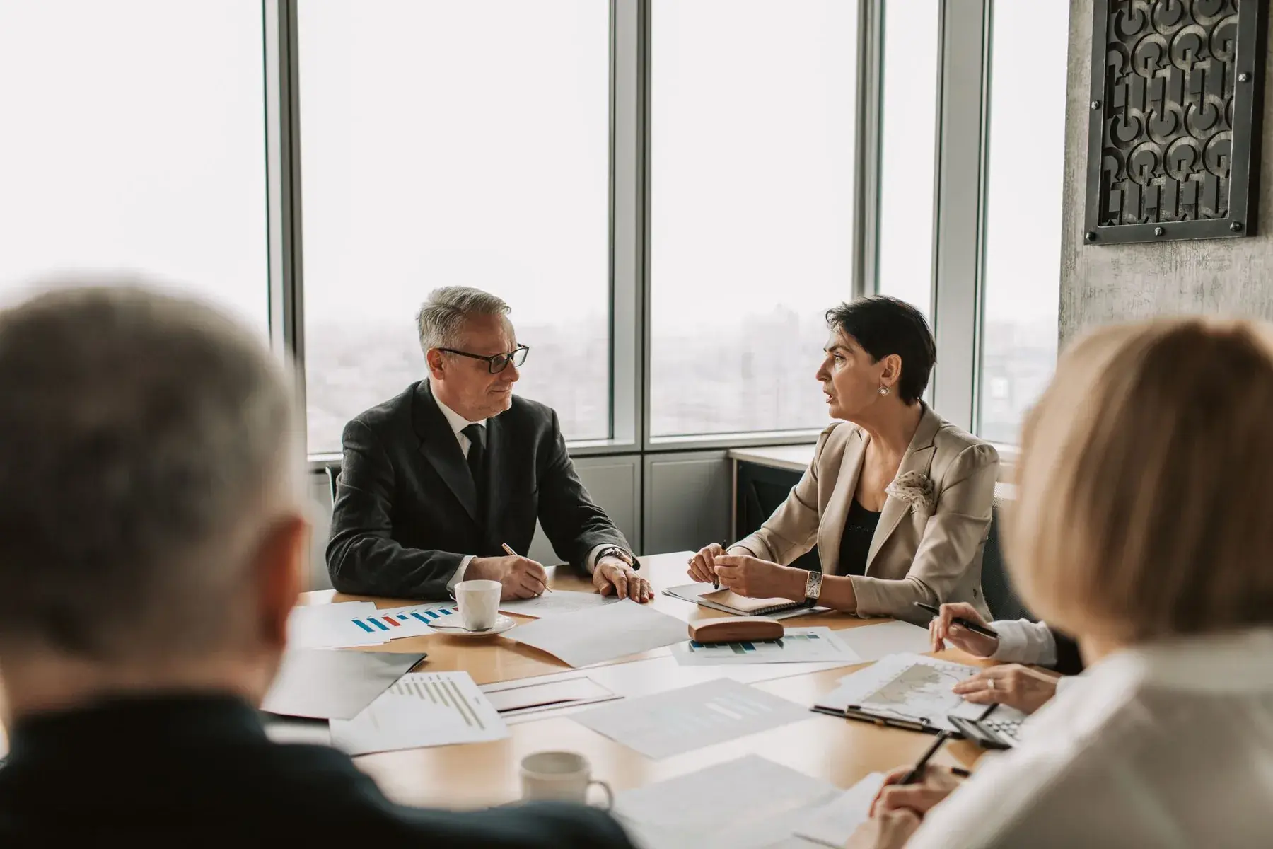 Two senior professionals in conversation at a boardroom table, representing Edu Accounting & Auditors' business advisory services