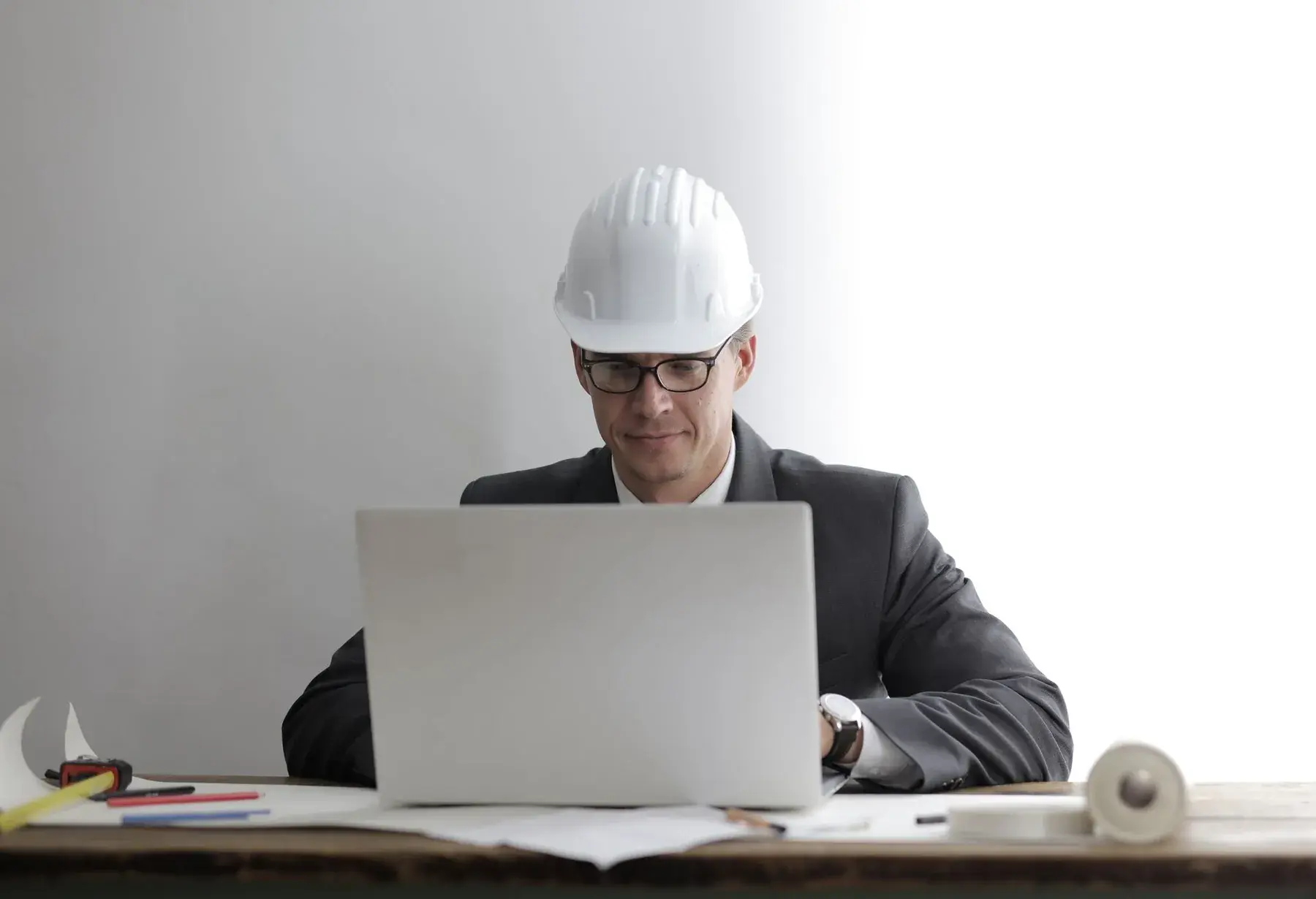 A professional in a hard hat working at a laptop, representing Edu Accounting & Auditors' CIDB and CSD services