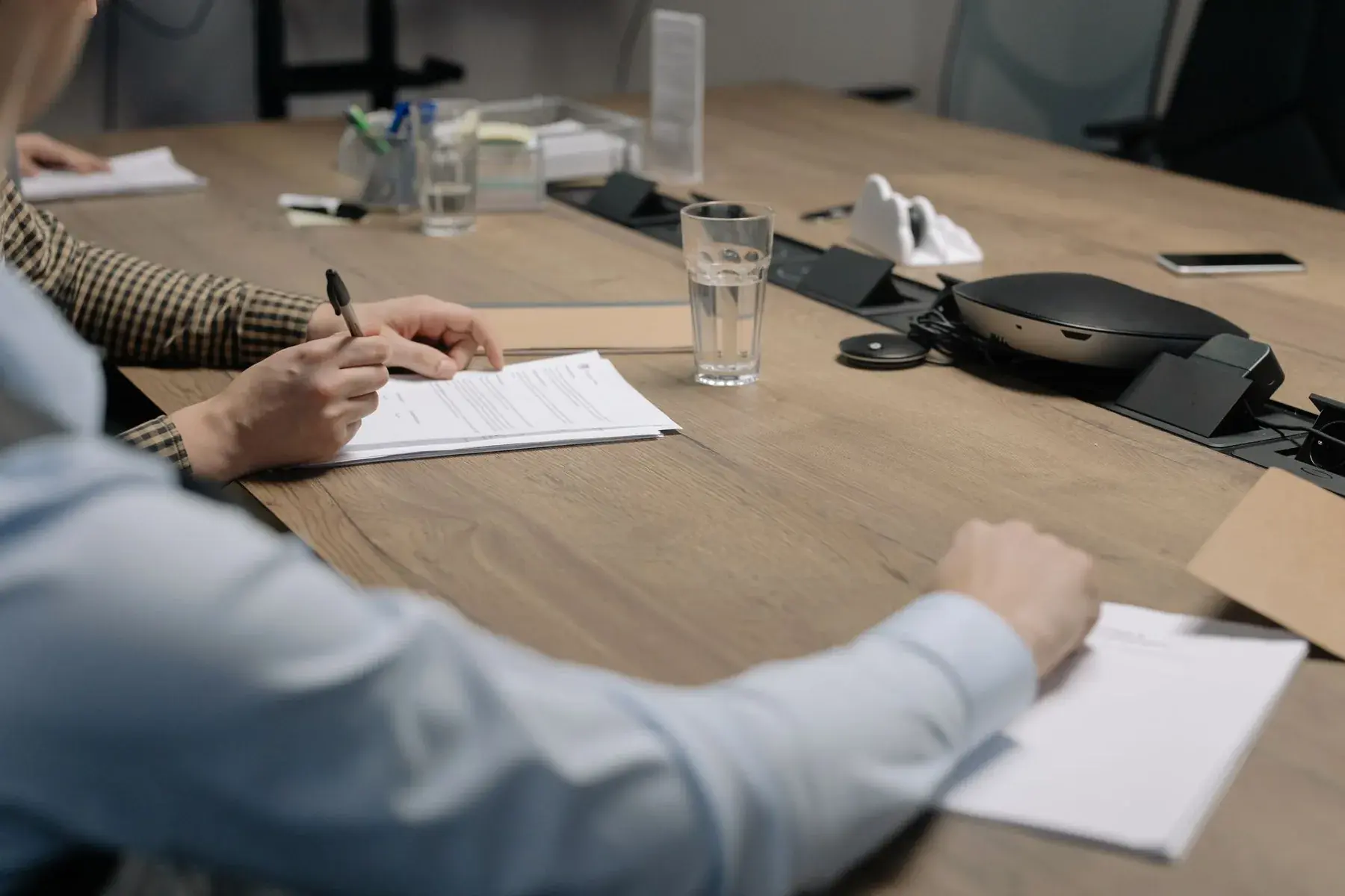 A hand signing a document with a pen in an office setting, representing Edu Accounting & Auditors' CIPC and compliance services