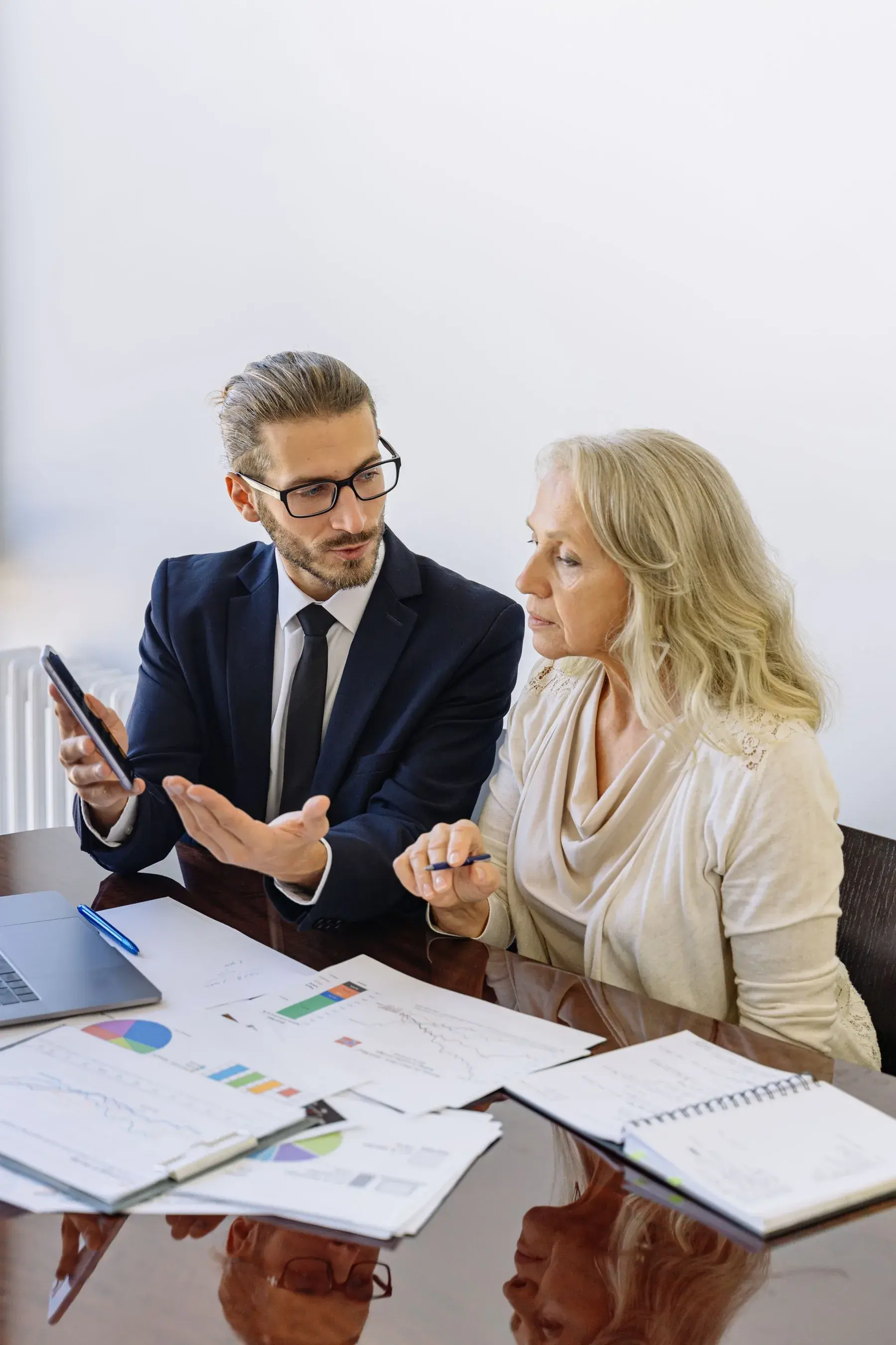 Two professionals reviewing financial charts and reports together at a table, representing Edu Accounting & Auditors' tax services